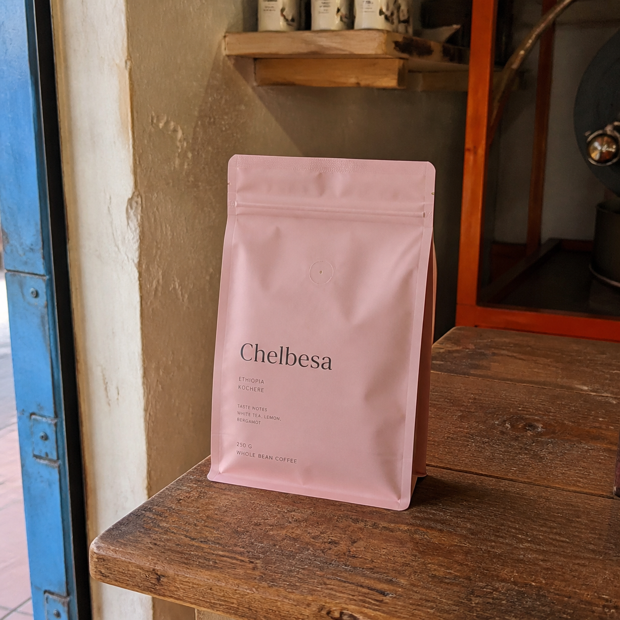 Sacchetto rosa di caffè Chelbesa, Etiopia, da 250 g su una mensola di legno