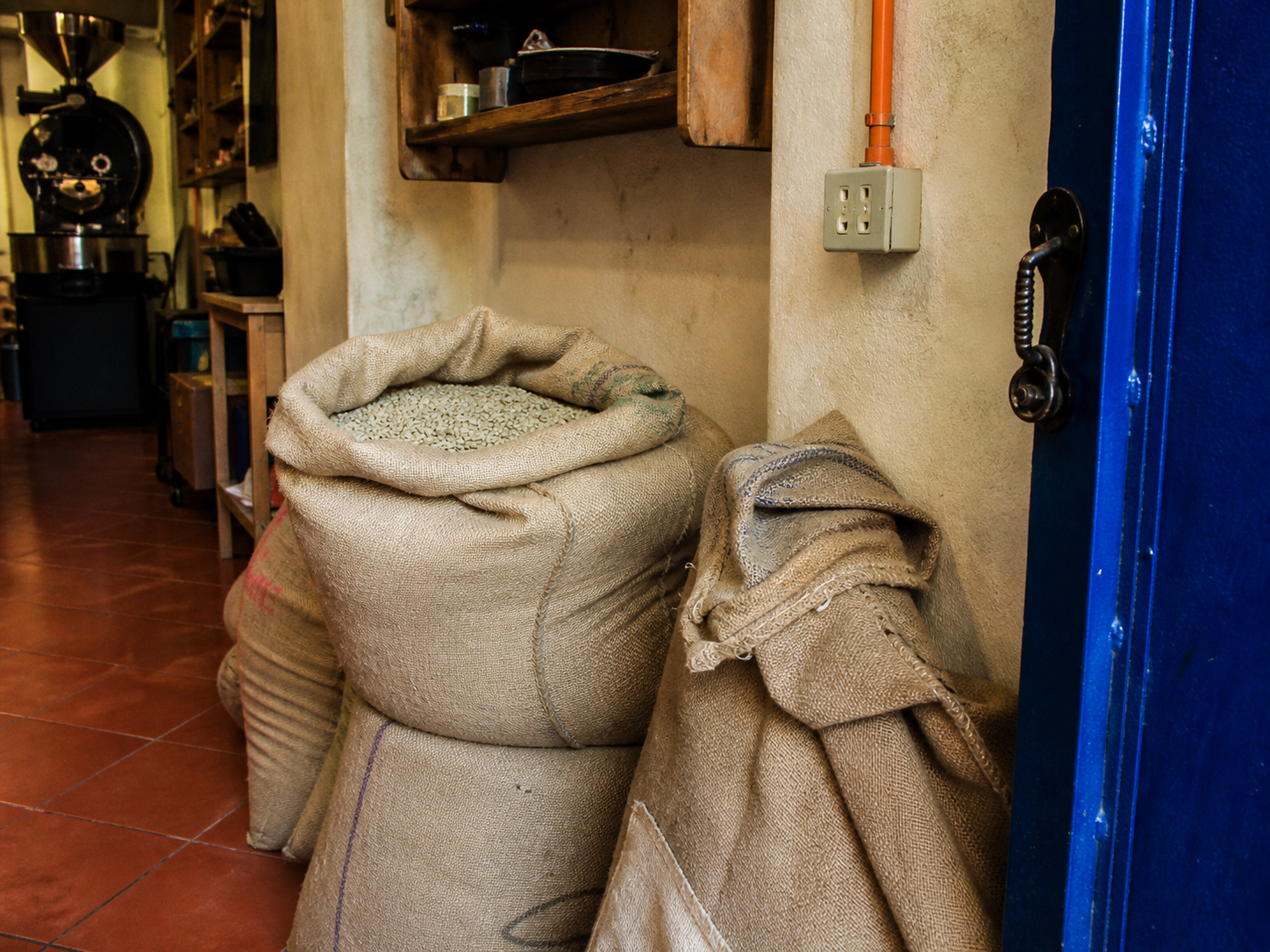 Sacchi di juta con caffè verde appoggiati al muro della torrefazione